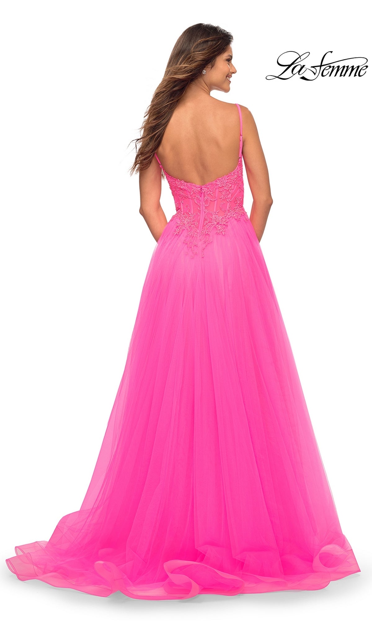 A woman faces away wearing the La Femme Neon Pink Long Ball Gown with Lace, featuring tulle, a low back, and thin straps. The La Femme logo is displayed in the top right corner.